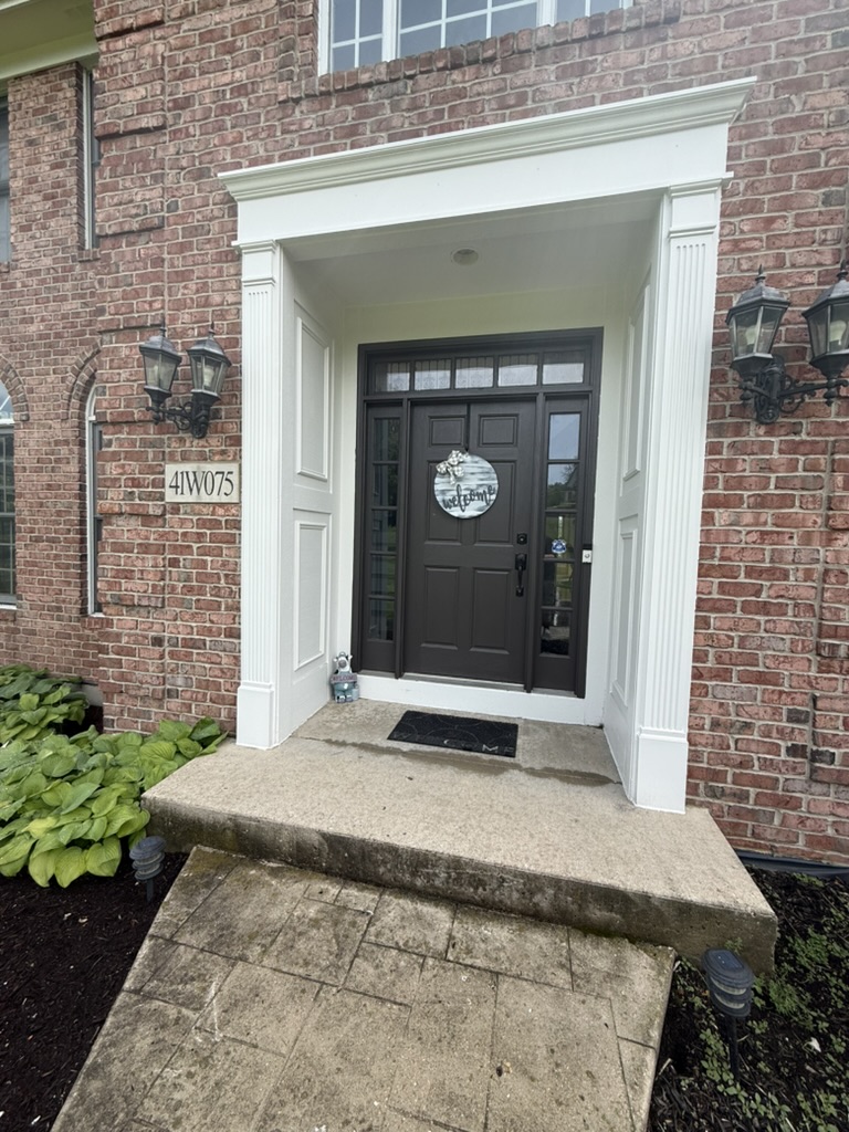 Dark front door surrounded by freshly painted white trim on a brick home